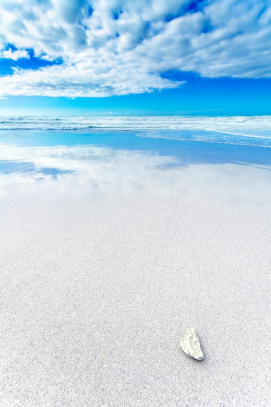 白色岩石中蓝色和多云的天空下的白色海滩