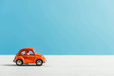 玩具紅色汽車的側(cè)視圖騎在白色表面在藍(lán)色背景