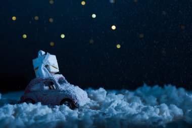 玩具汽車(chē)的特寫(xiě)鏡頭與禮品盒站在雪中的夜晚, 圣誕節(jié)概念
