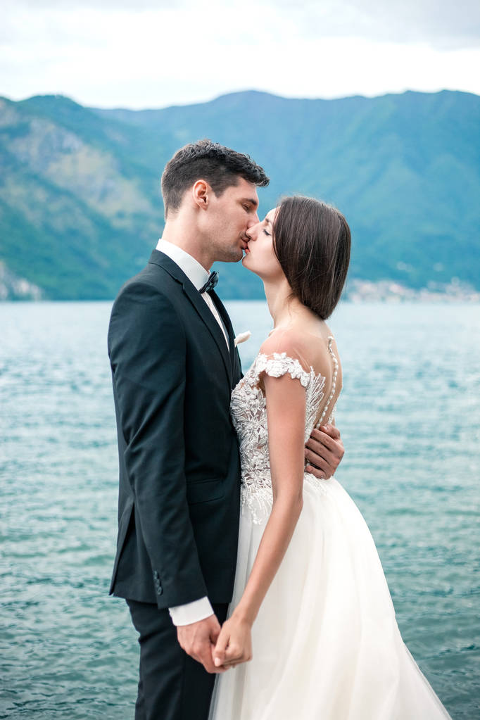 新婚夫妇接吻的背景下的湖泊和山区在晚上