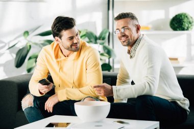 微笑的兒子和成熟的父親一起看電視在周末在家