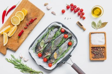 從上面看魚裝飾的迷迭香和櫻桃西紅柿在托盤與烘焙紙