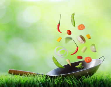 新鮮蔬菜在鍋中正在下降。烹飪的概念