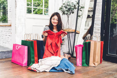 快樂的女人購物和選擇衣服在商店與五顏六色的購物袋. 時尚購物的概念