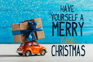 玩具車特寫與禮品盒在藍色木頭背景與“有你自己的快樂小圣誕節(jié)”的靈感