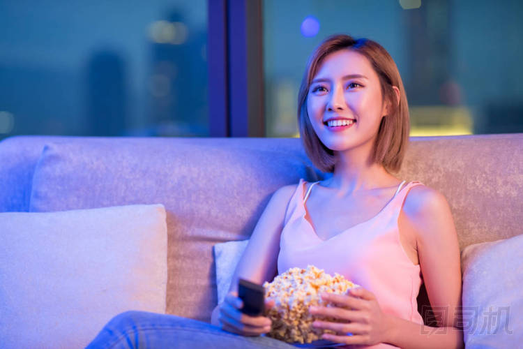 晚上看電視、吃爆米花的年輕女子
