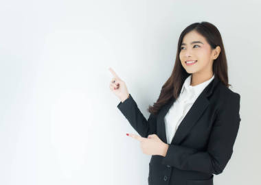 年輕的亞洲商界女性的肖像指向超過(guò)白色背景.