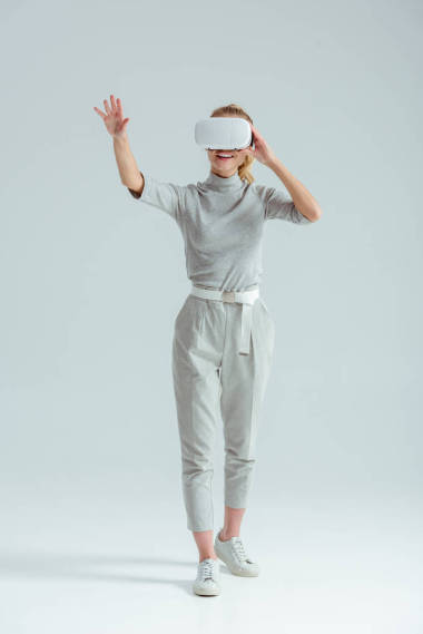 興奮的女孩在灰色服裝手勢(shì), 而有虛擬現(xiàn)實(shí)經(jīng)驗(yàn)的灰色背景