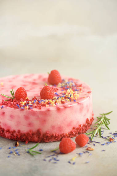 美味的覆盆子蛋糕与新鲜的浆果, 迷迭香和干花在灰色的混凝土背景。复制文本的空间。素食, 素食主义者的食物概念