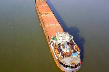 一艘貨船在河邊漂浮。貨船圖片