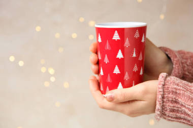 节日背景下手拿着红色一次性玻璃。概念圣诞节。复制空间