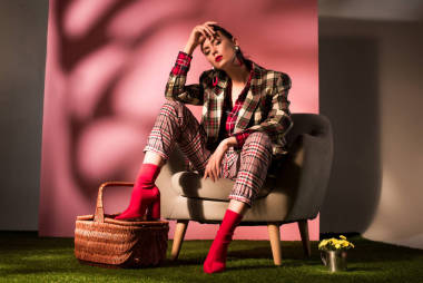 美麗優(yōu)雅的女孩在格子西裝擺在扶手椅與籃子在粉紅色的背景