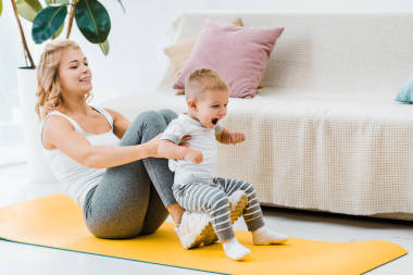 母親坐在健身墊上, 同時(shí)把孩子抬到空氣中