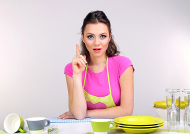 美麗的年輕女子在灰色的背景上的廚房濕巾清潔用具