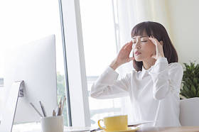 穿着白色西装的年轻女子双手放在她的头上, 看上去很痛苦