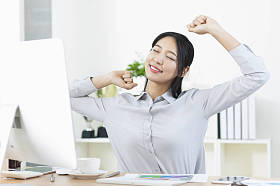 年轻的亚洲女人坐在桌旁, 伸展身体