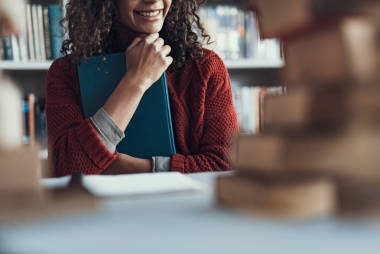 親密的微笑的夫人按書對(duì)她的胸口