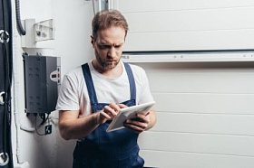 严重的成人电工使用数字平板电脑附近的电气盒
