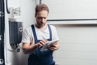 严重的成人电工使用数字平板电脑附近的电气盒