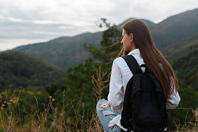 在山的背景下背包的年轻女孩照片