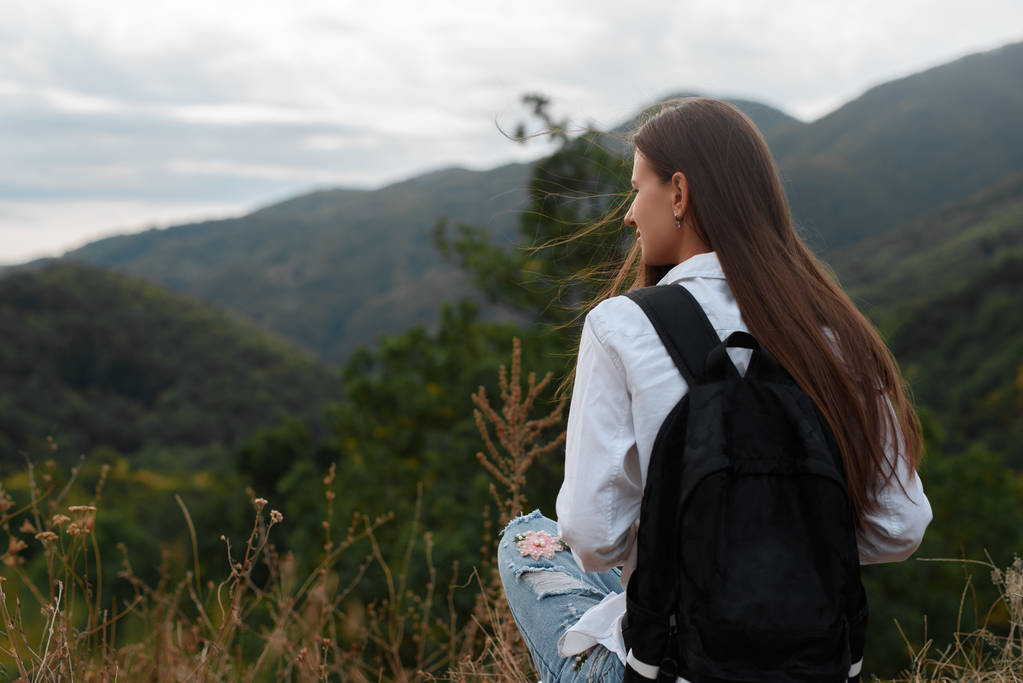 在山的背景下背包的年轻女孩照片