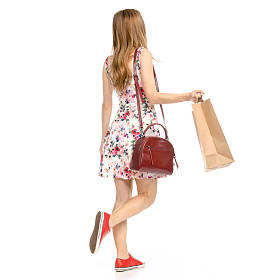 美丽的女人在礼服与鲜花打印和运动鞋显示积极的情绪运行与包包