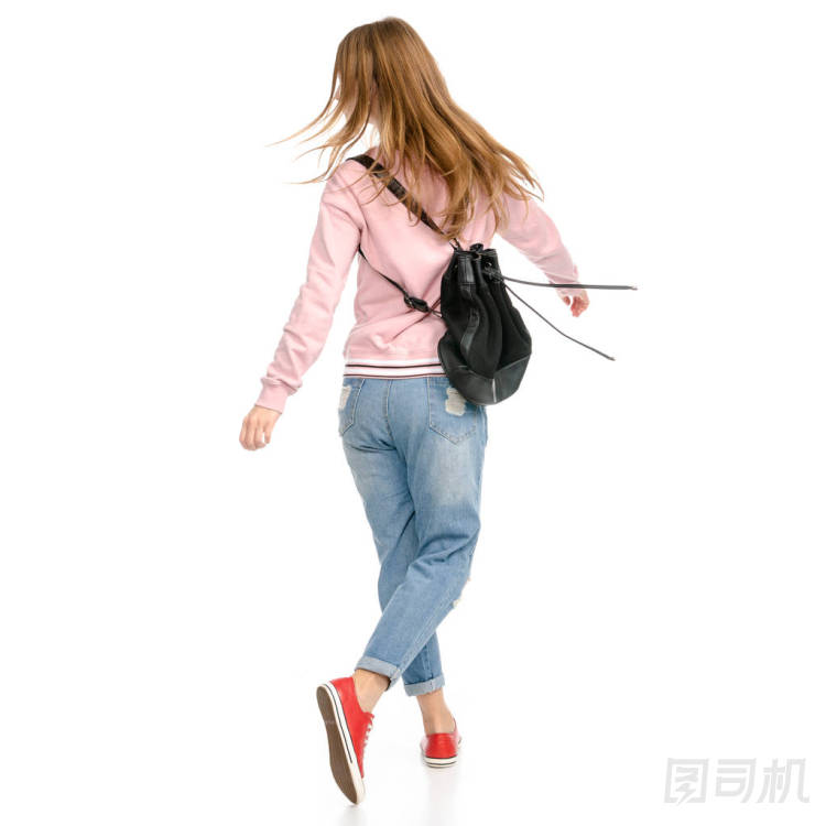 美麗的女人在牛仔褲與背包走去