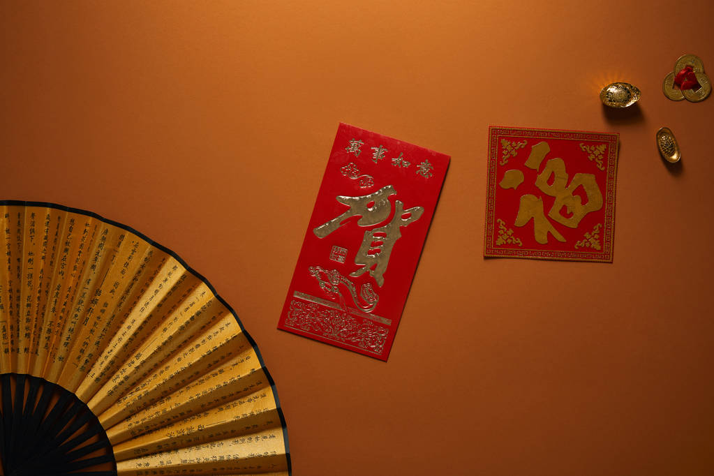 风扇的顶视图与象形文字和金黄装饰在棕色背景, 中国新年构成