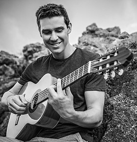 帅哥微笑着吉他弹奏者播放音乐选址上海滩岩