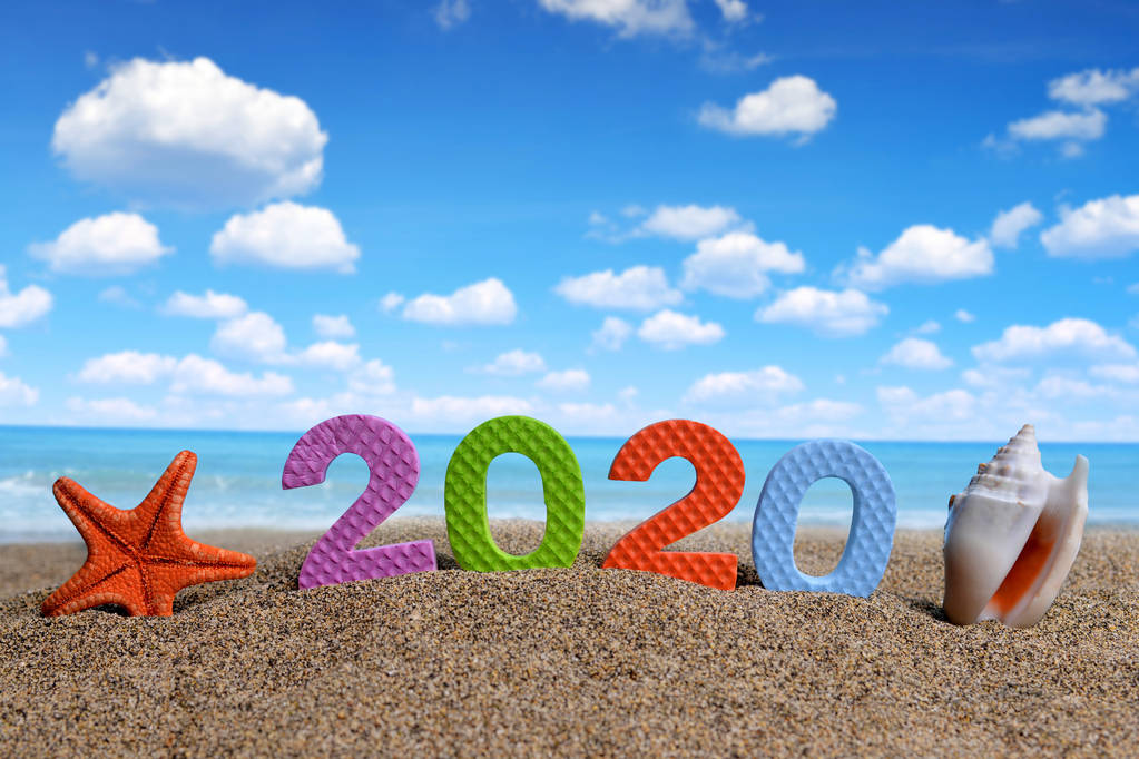 2020号和海贝壳与海星在沙滩上。新年快乐和暑假概念