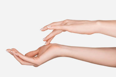 裁剪視圖的婦女應(yīng)用保濕手霜隔離在白色