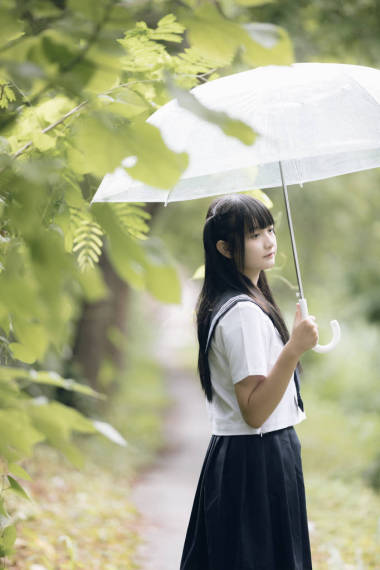 在雨中漫步在自然人行道上的亞洲學(xué)校女孩肖像