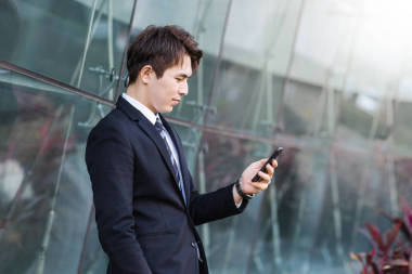 商务人士使用具有城市建筑背景的智能手机 