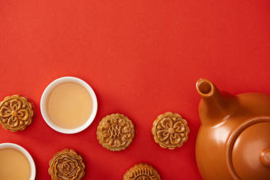 在紅色上隔離的傳統(tǒng)月餅、茶壺和杯子的頂視圖