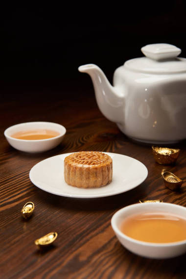 傳統(tǒng)的月餅與茶杯, 鍋和金錠隔離在黑色