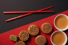 红色和黑色背景上的传统中国月饼与筷子的顶部视图