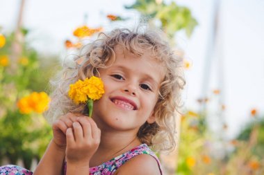 微笑的卷曲的女孩的画像摆与黄色万寿菊花