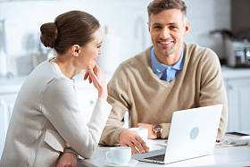 成年夫妇在早餐时在早餐时使用笔记本电脑的选择性焦点