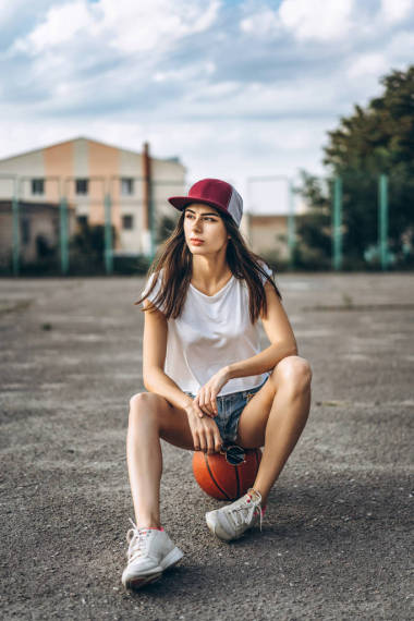 相当年轻运动的女孩与篮球室外