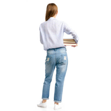 婦女在藍(lán)色牛仔褲和襯衫與書在手去