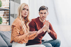 年轻人看着震惊的女友拿着智能手机, 看着相机, 不信任的概念