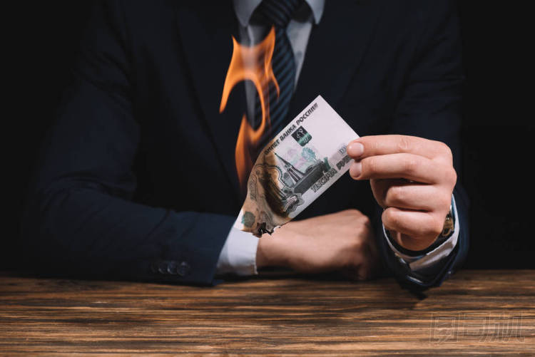 裁剪拍攝的商人燃燒俄羅斯盧布鈔票以上的木桌 