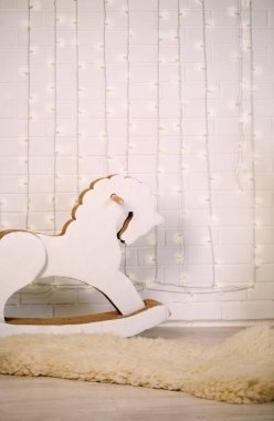 摇马在一堵砖墙与灯泡一个花环的背景