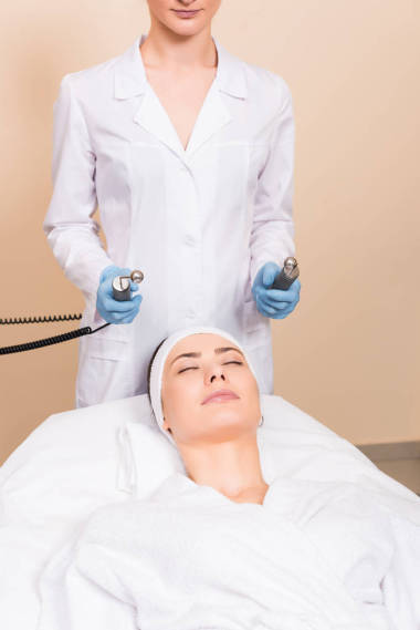 美容師舉行提升按摩器在女人的臉在美容院