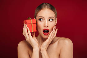 一个有吸引力的金发碧眼的女人站在红色的背景孤立的美丽的肖像, 拿着礼品盒