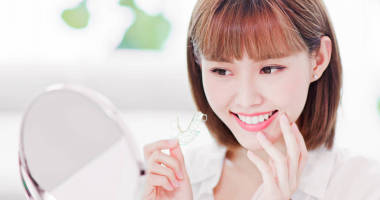 美女脫下牙的支撐架后, 高興地看著鏡子里美麗的牙齒