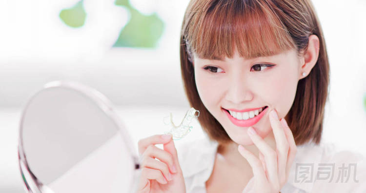 美女脫下牙的支撐架后, 高興地看著鏡子里美麗的牙齒