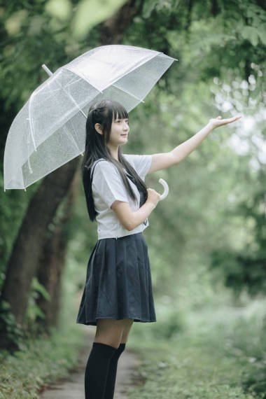 在雨中漫步在自然人行道上的亞洲學(xué)校女孩肖像