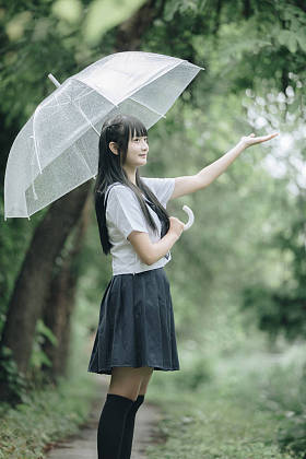 在雨中漫步在自然人行道上的亚洲学校女孩肖像