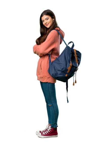 一個(gè)穿著運(yùn)動(dòng)衫和背包的少年女孩的全長(zhǎng)照片, 在微笑的時(shí)候, 把手臂交叉在側(cè)向的位置上